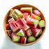 Wooden bowl filled with red and green striped candy on a white background