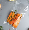 Vacuum-sealed salmon fillets with herbs on a gray surface